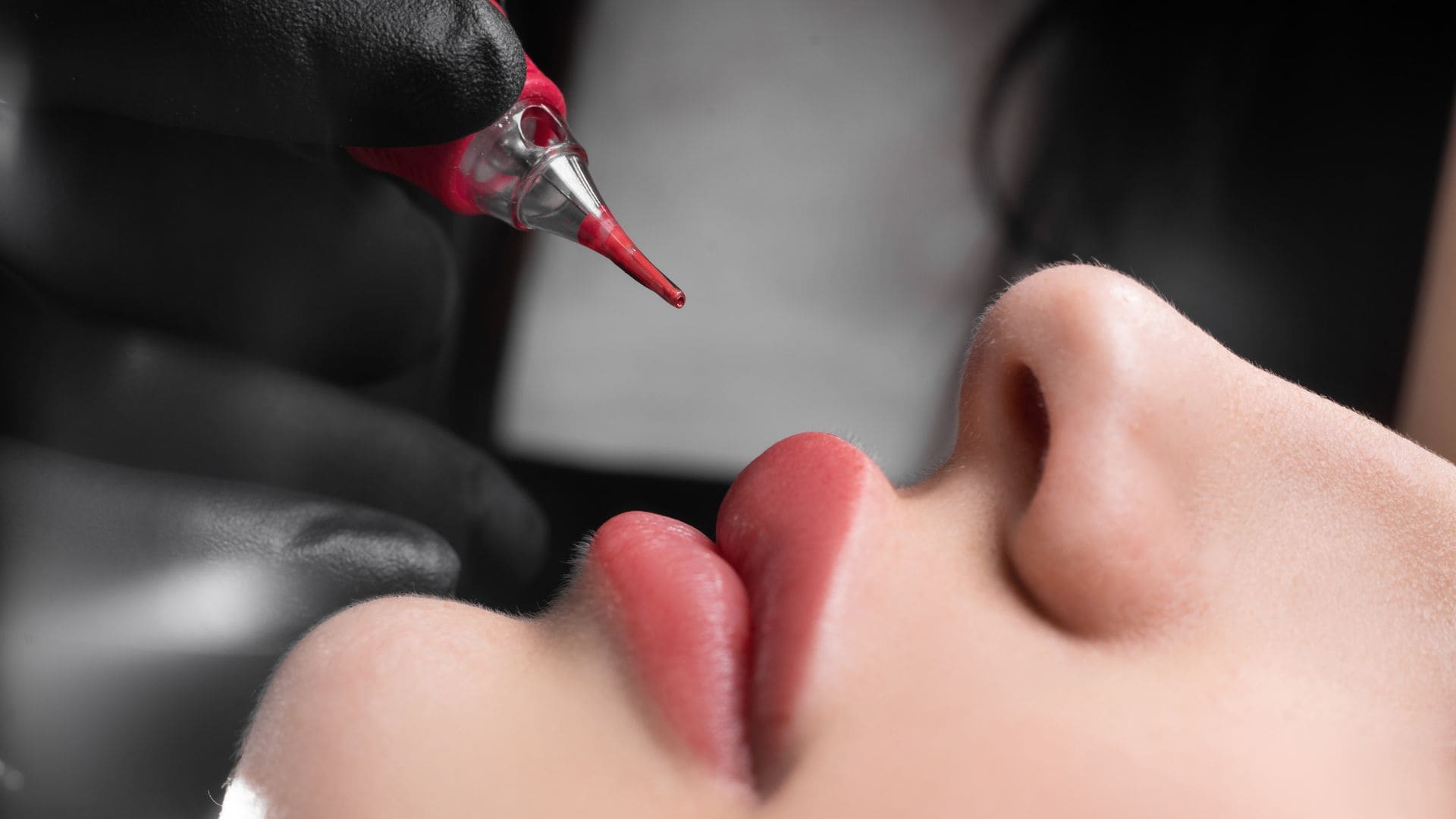 Nahaufnahme von Permanent-Make-up an den Lippen, Pigment wird mit einer feinen Nadel aufgetragen.